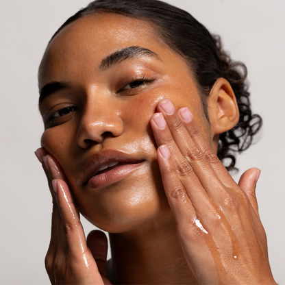 Woman applying Cosmette skincare product to her face with a neutral background