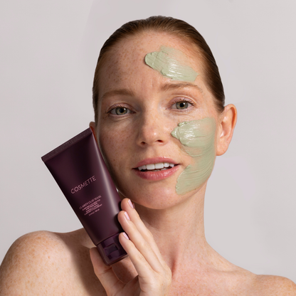 Woman applying cosmette clarity clay mask on a plain background