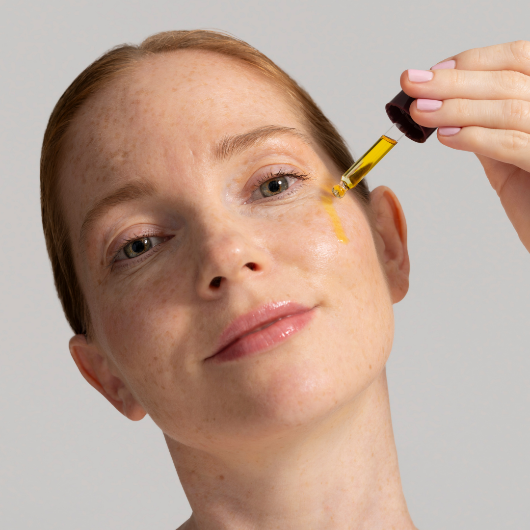 Person applying a dropper of Rose Garden to their face against a neutral background